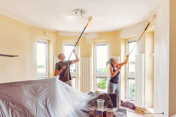 Couple renovating home painting ceiling