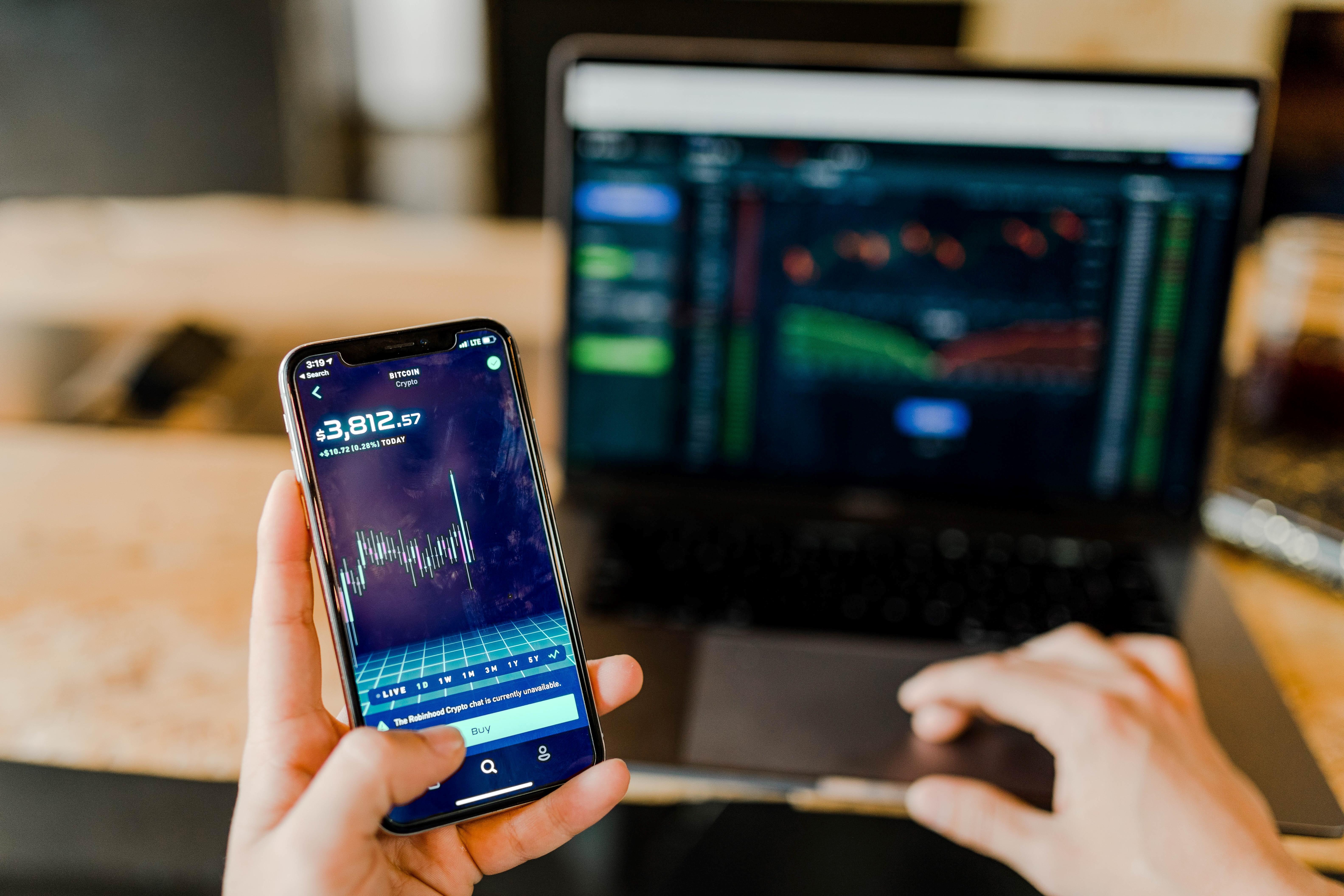 Person looking at stocks on phone and laptop