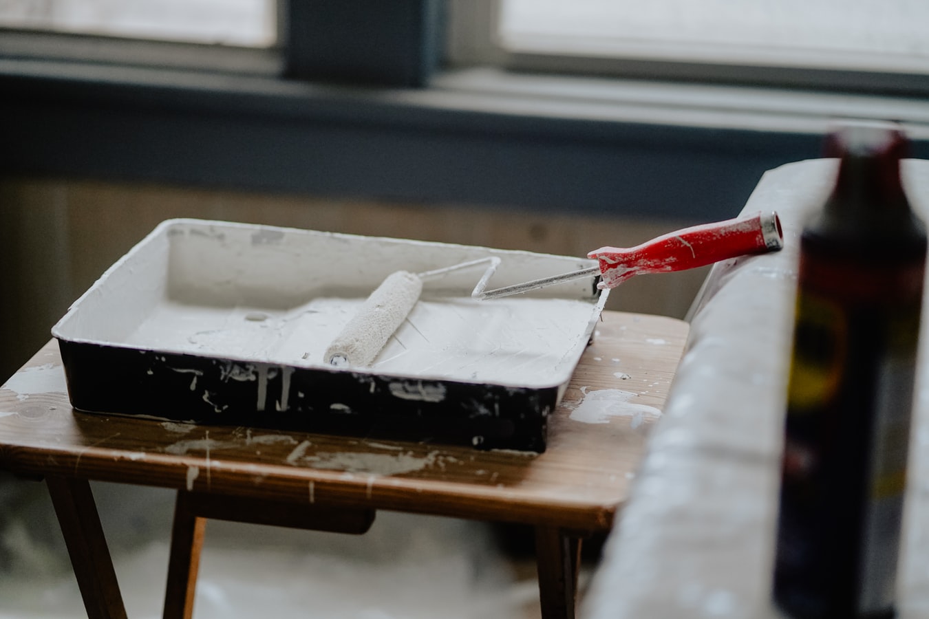 Paint tray with white paint and roller inside