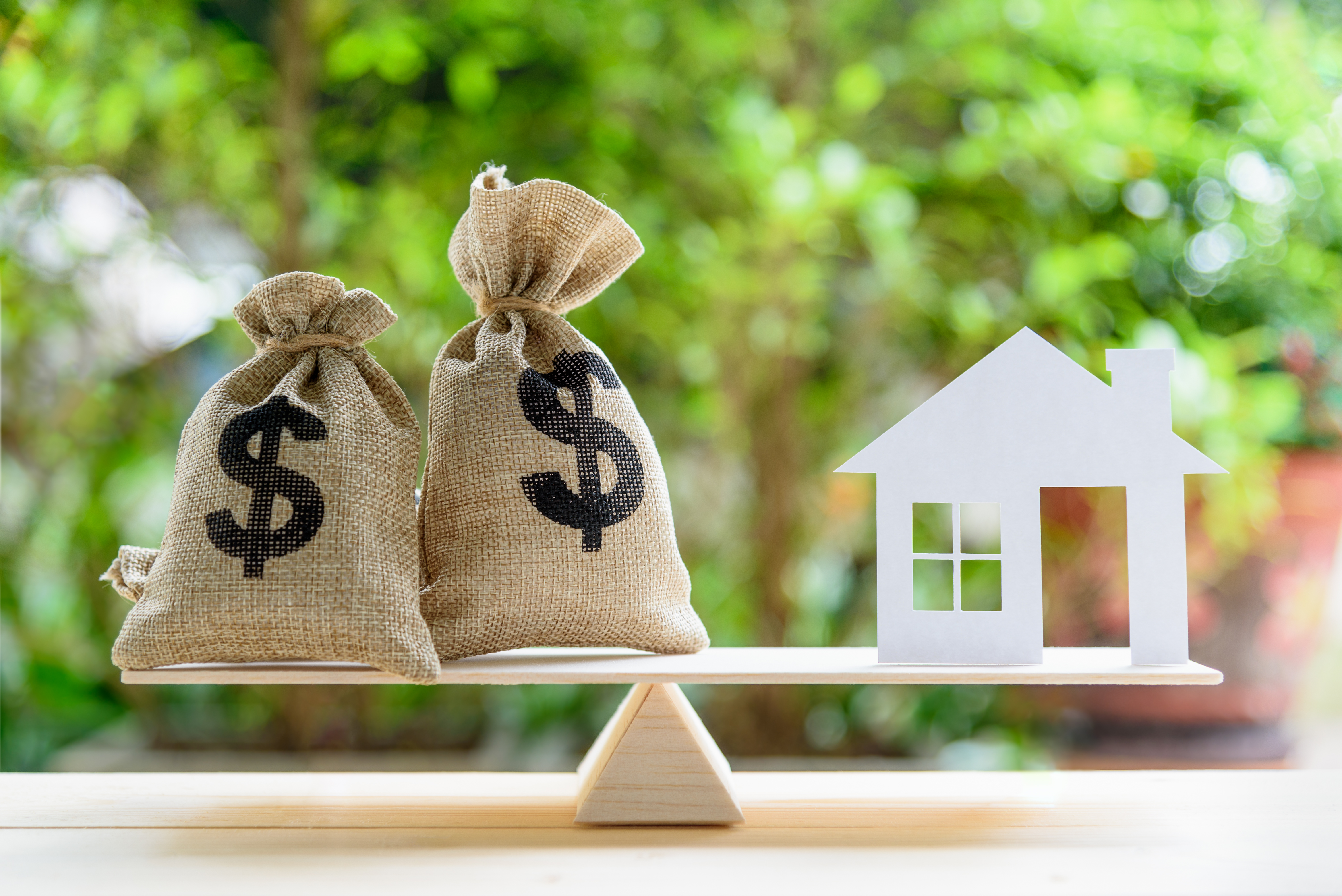 Balance scale with home and money bag