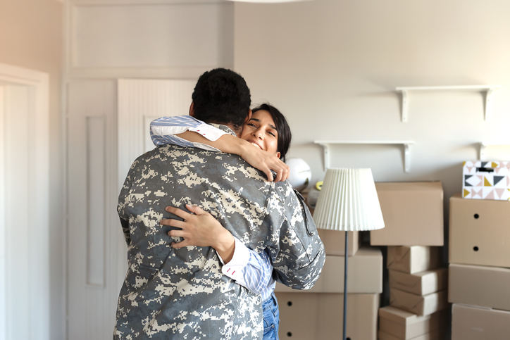 Military couple hugging in front of boxes